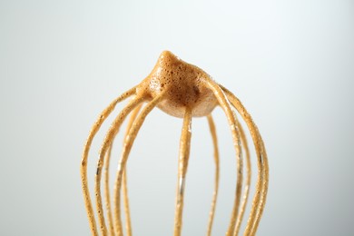 Photo of Making delicious dalgona coffee. Whisk with cream on light grey background, closeup