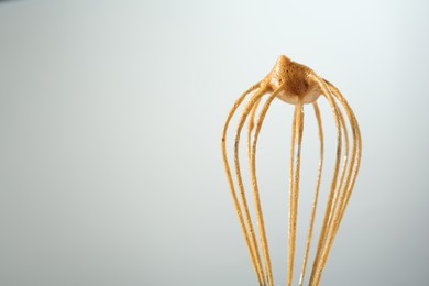 Photo of Making delicious dalgona coffee. Whisk with cream on light grey background, closeup. Space for text