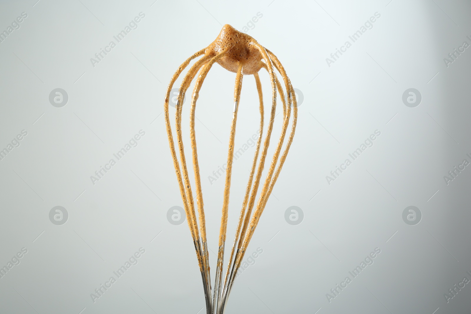 Making delicious dalgona coffee. Whisk with cream on light grey background, closeup Photo of Making delicious dalgona coffee. Whisk with cream on light grey background, closeup