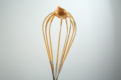 Photo of Making delicious dalgona coffee. Whisk with cream on light grey background, closeup
