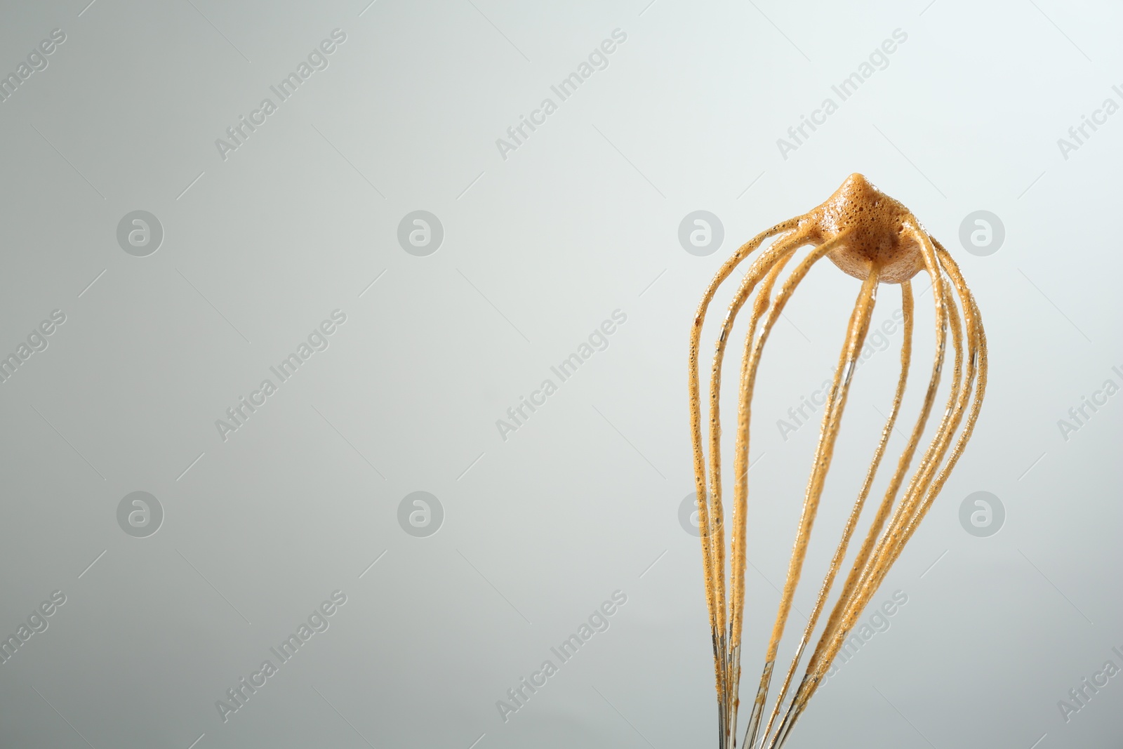 Making delicious dalgona coffee. Whisk with cream on light grey background, closeup. Space for text Photo of Making delicious dalgona coffee. Whisk with cream on light grey background, closeup. Space for text