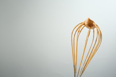 Photo of Making delicious dalgona coffee. Whisk with cream on light grey background, closeup. Space for text