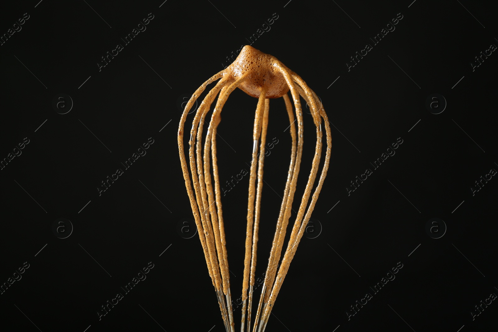 Photo of Making delicious dalgona coffee. Whisk with cream on black background, closeup
