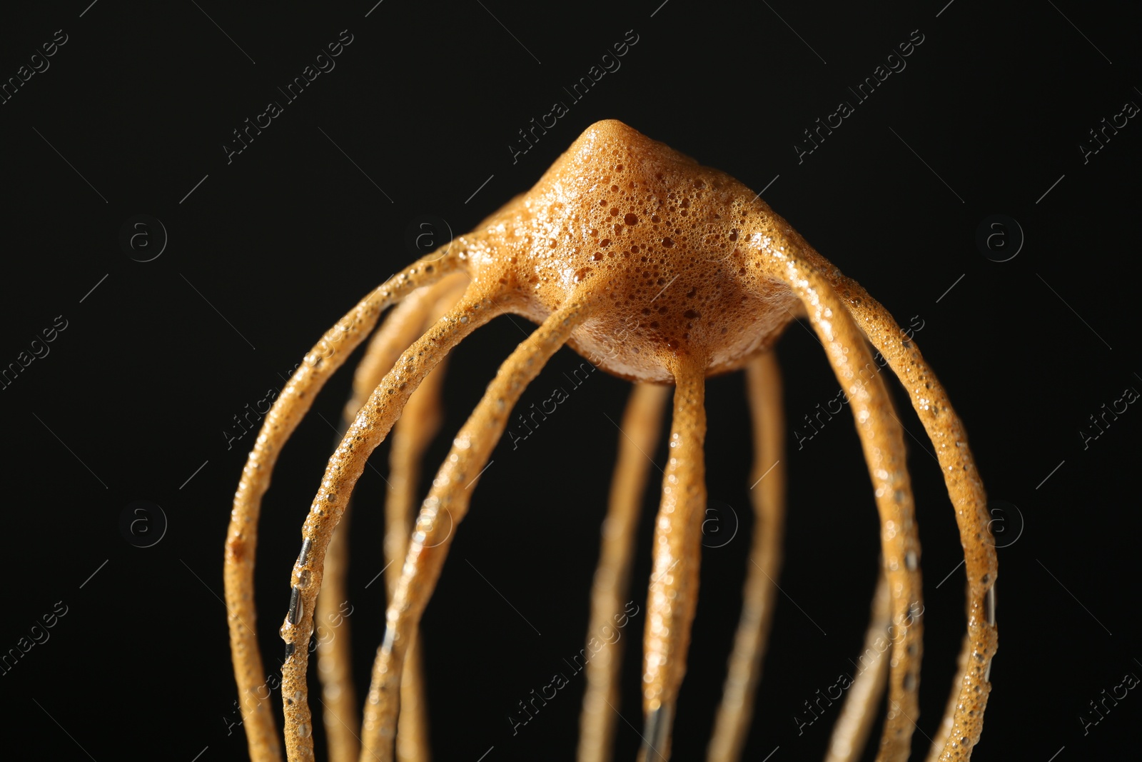 Photo of Making delicious dalgona coffee. Whisk with cream on black background, closeup