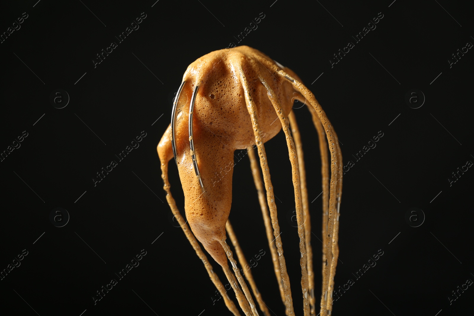 Photo of Making delicious dalgona coffee. Whisk with cream on black background, closeup