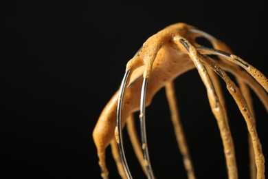 Photo of Making delicious dalgona coffee. Whisk with cream on black background, closeup. Space for text