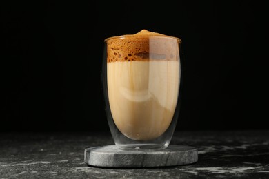 Photo of Delicious dalgona coffee in glass on dark marble table
