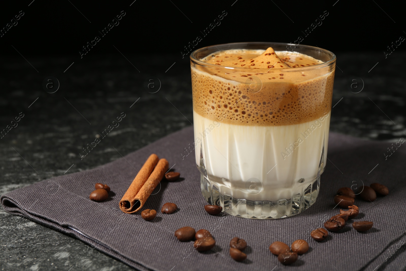 Delicious dalgona coffee in glass, beans and cinnamon on dark marble table, closeup. Space for text Photo of Delicious dalgona coffee in glass, beans and cinnamon on dark marble table, closeup. Space for text
