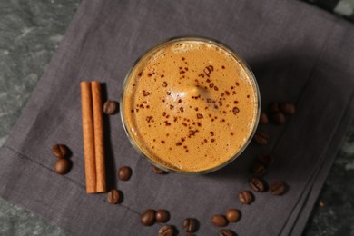 Photo of Delicious dalgona coffee in glass, beans and cinnamon on dark table, top view