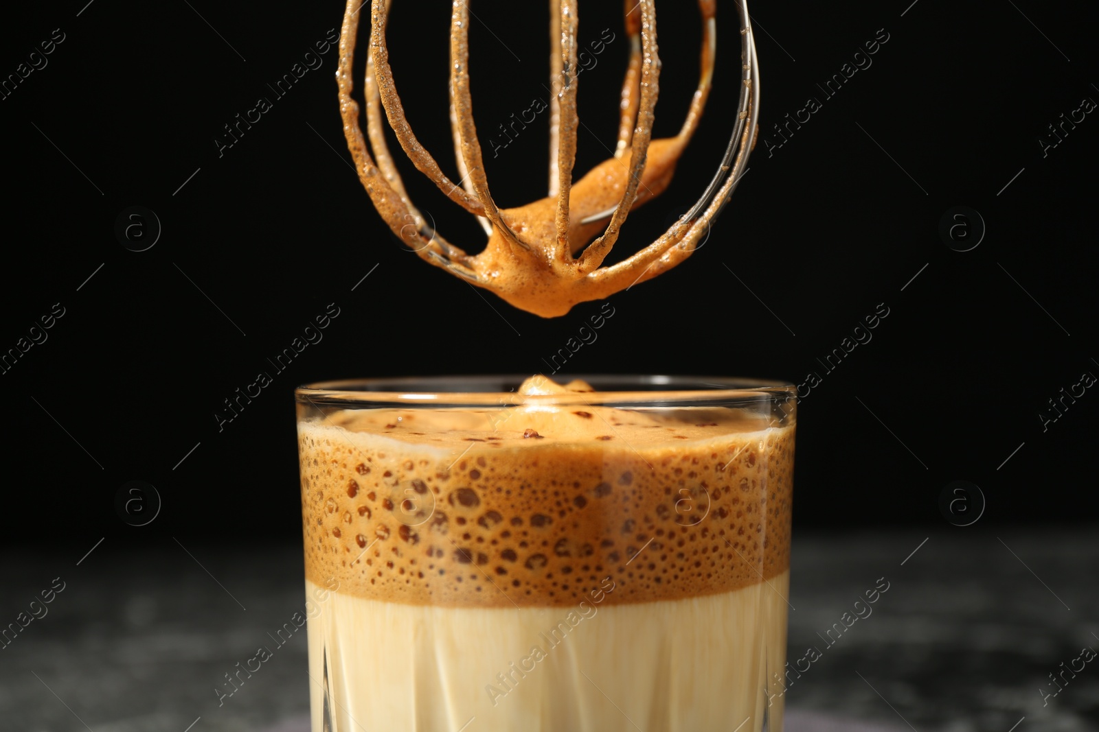 Pouring cream for dalgona coffee into glass on blurred background, closeup Photo of Pouring cream for dalgona coffee into glass on blurred background, closeup