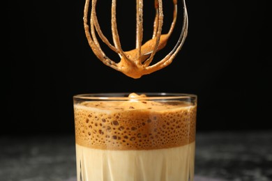 Photo of Pouring cream for dalgona coffee into glass on blurred background, closeup