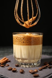 Photo of Pouring cream for dalgona coffee into glass at table, closeup