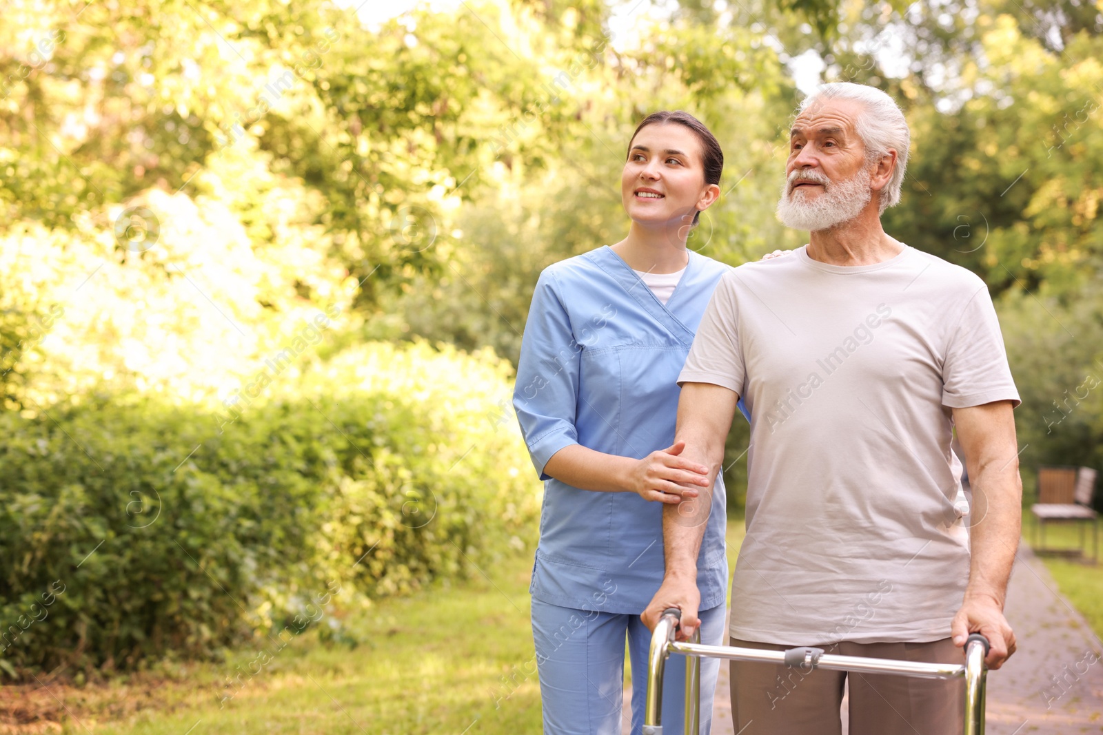 Smiling nurse with elderly man who using walking frame outdoors. Space for text Photo of Smiling nurse with elderly man who using walking frame outdoors. Space for text
