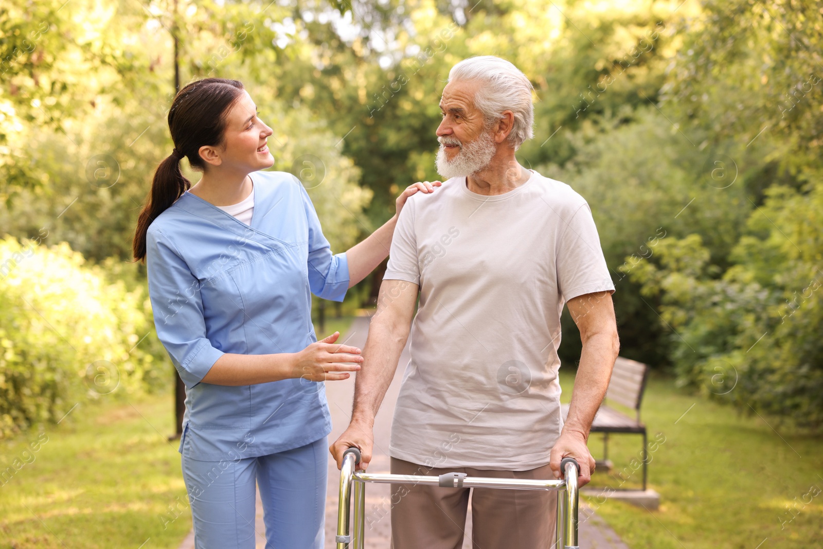 Smiling nurse supporting elderly man who using walking frame outdoors Photo of Smiling nurse supporting elderly man who using walking frame outdoors