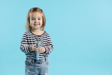 Photo of Cute little girl with microphone on light blue background, space for text
