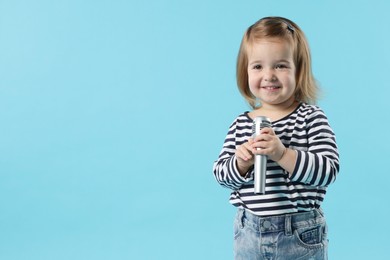Photo of Cute little girl with microphone on light blue background, space for text