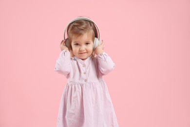 Photo of Cute little girl in headphones on pink background