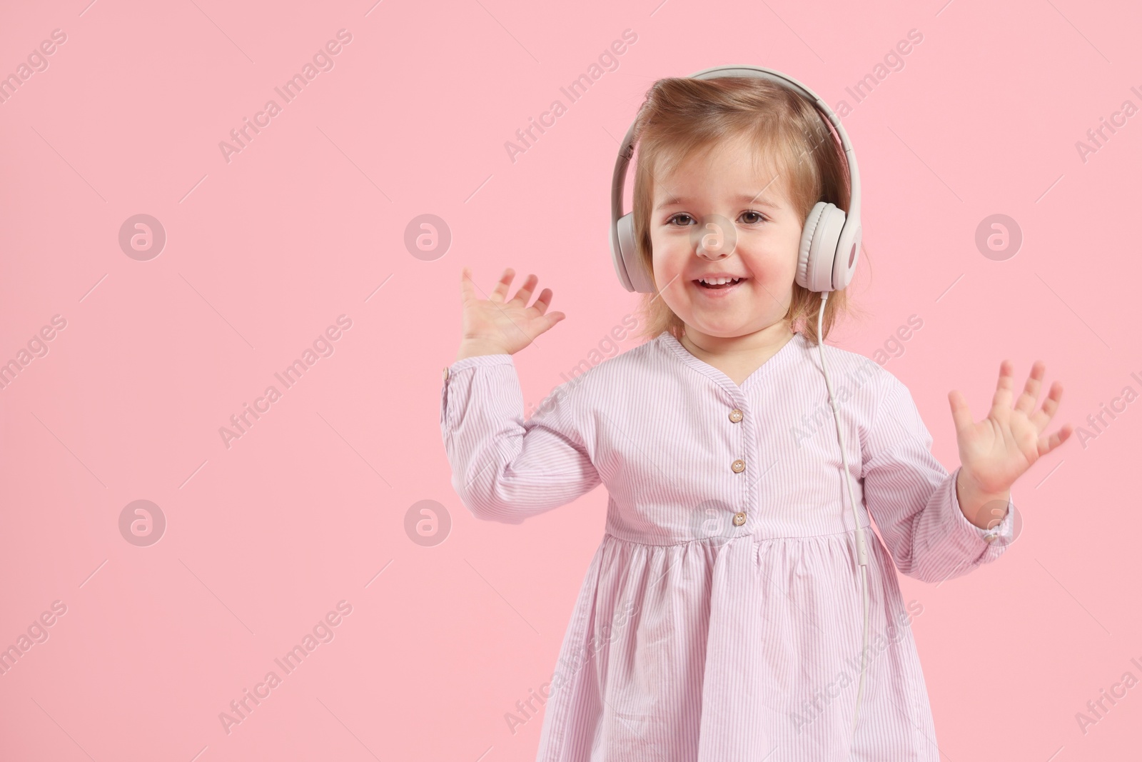Cute little girl in headphones on pink background, space for text Photo of Cute little girl in headphones on pink background, space for text
