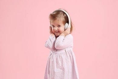 Photo of Cute little girl in headphones on pink background