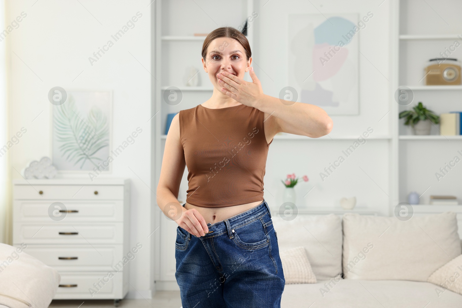 Beautiful woman wearing old jeans after weight loss indoors Photo of Beautiful woman wearing old jeans after weight loss indoors