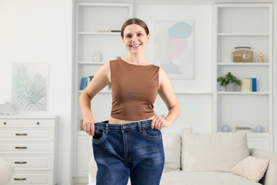 Photo of Beautiful woman wearing old jeans after weight loss indoors