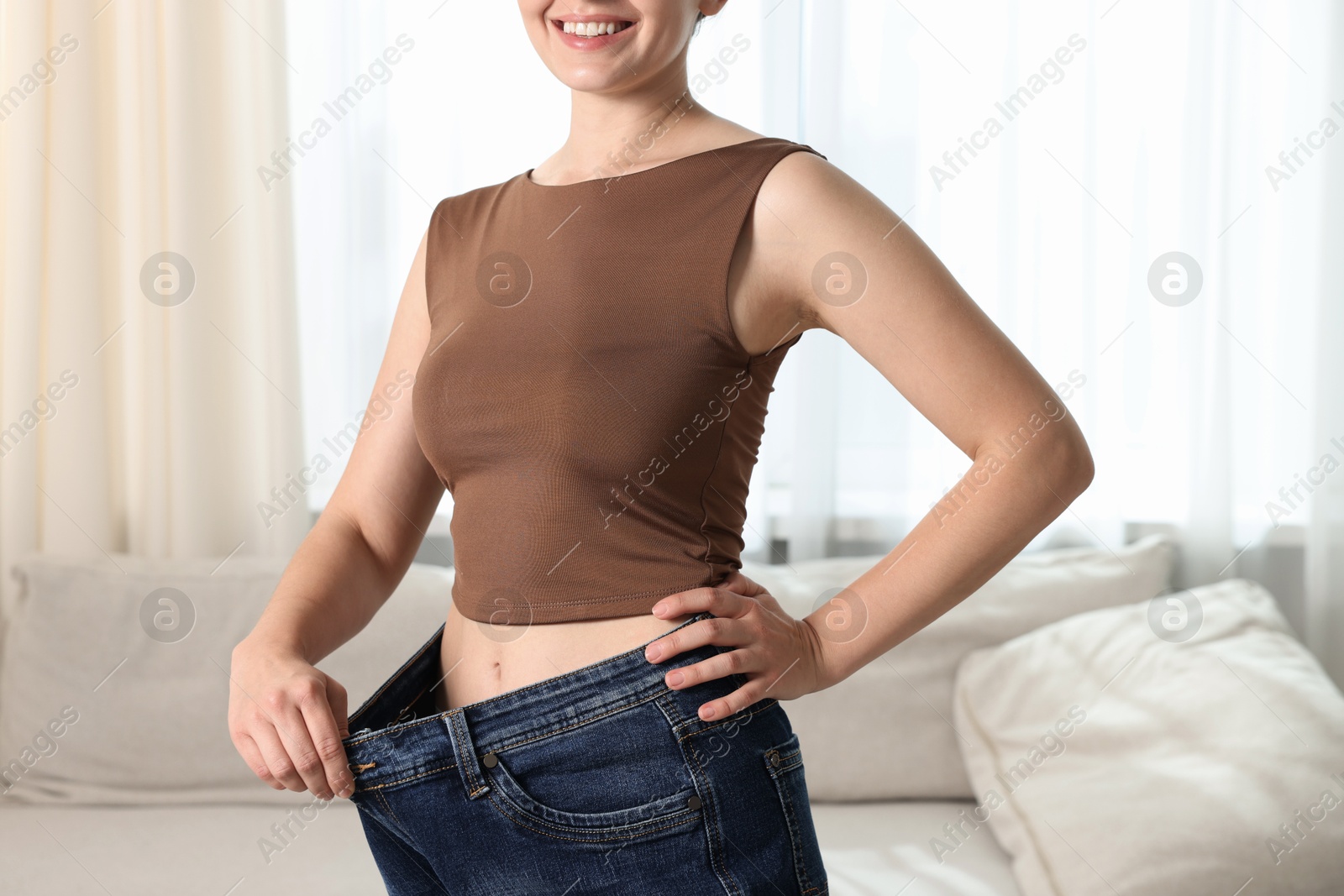 Woman wearing old jeans after weight loss indoors, closeup Photo of Woman wearing old jeans after weight loss indoors, closeup