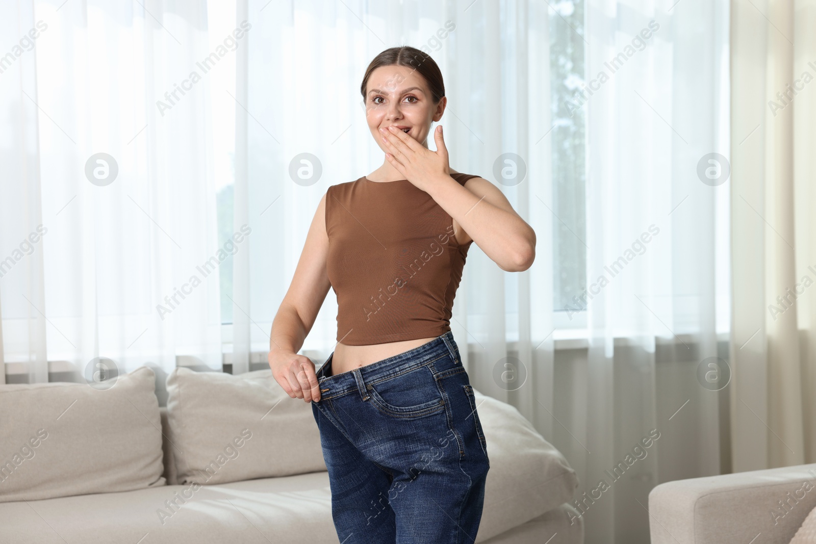Beautiful woman wearing old jeans after weight loss indoors Photo of Beautiful woman wearing old jeans after weight loss indoors