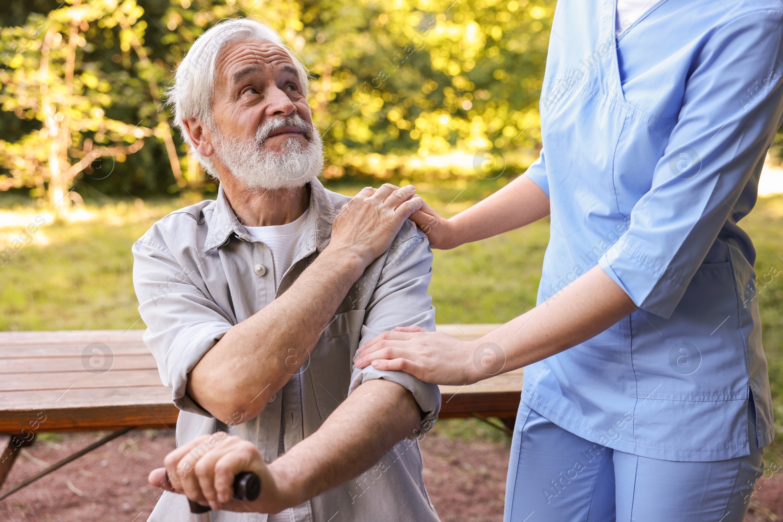 Nurse supporting elderly man with walking cane outdoors, closeup Photo of Nurse supporting elderly man with walking cane outdoors, closeup