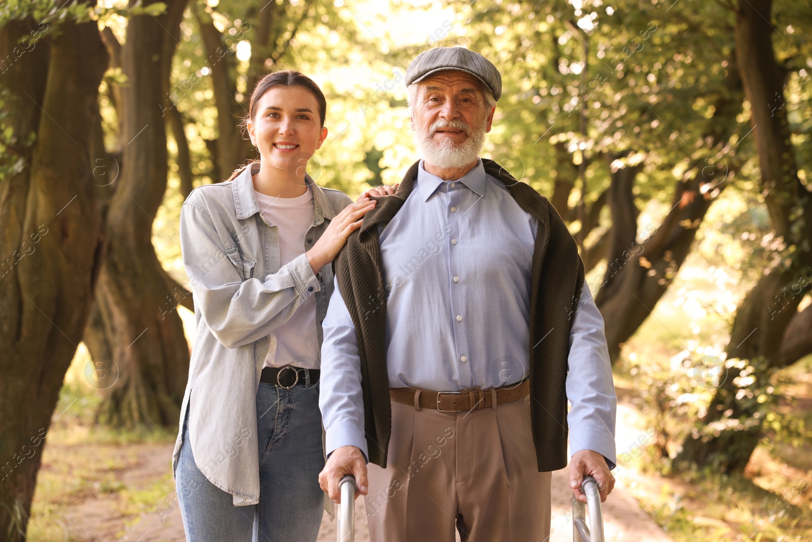 Smiling caregiver supporting elderly man who using walking frame outdoors Photo of Smiling caregiver supporting elderly man who using walking frame outdoors