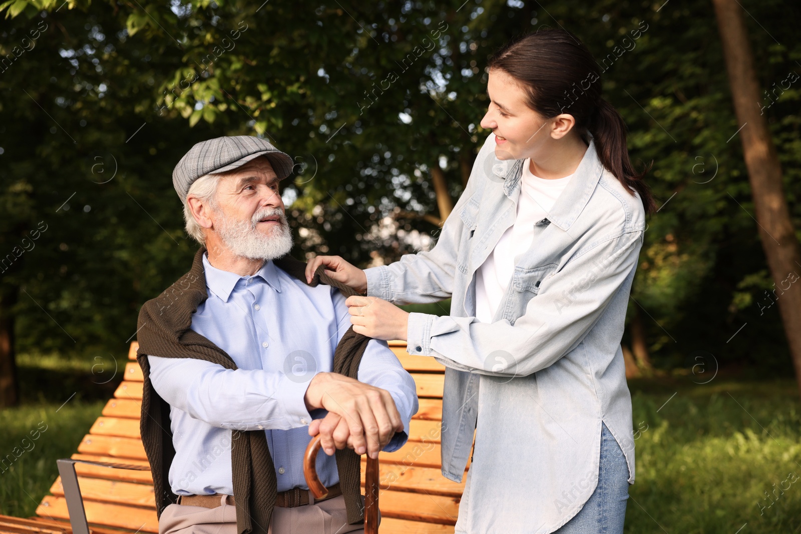 Smiling caregiver supporting elderly man with walking cane outdoors Photo of Smiling caregiver supporting elderly man with walking cane outdoors