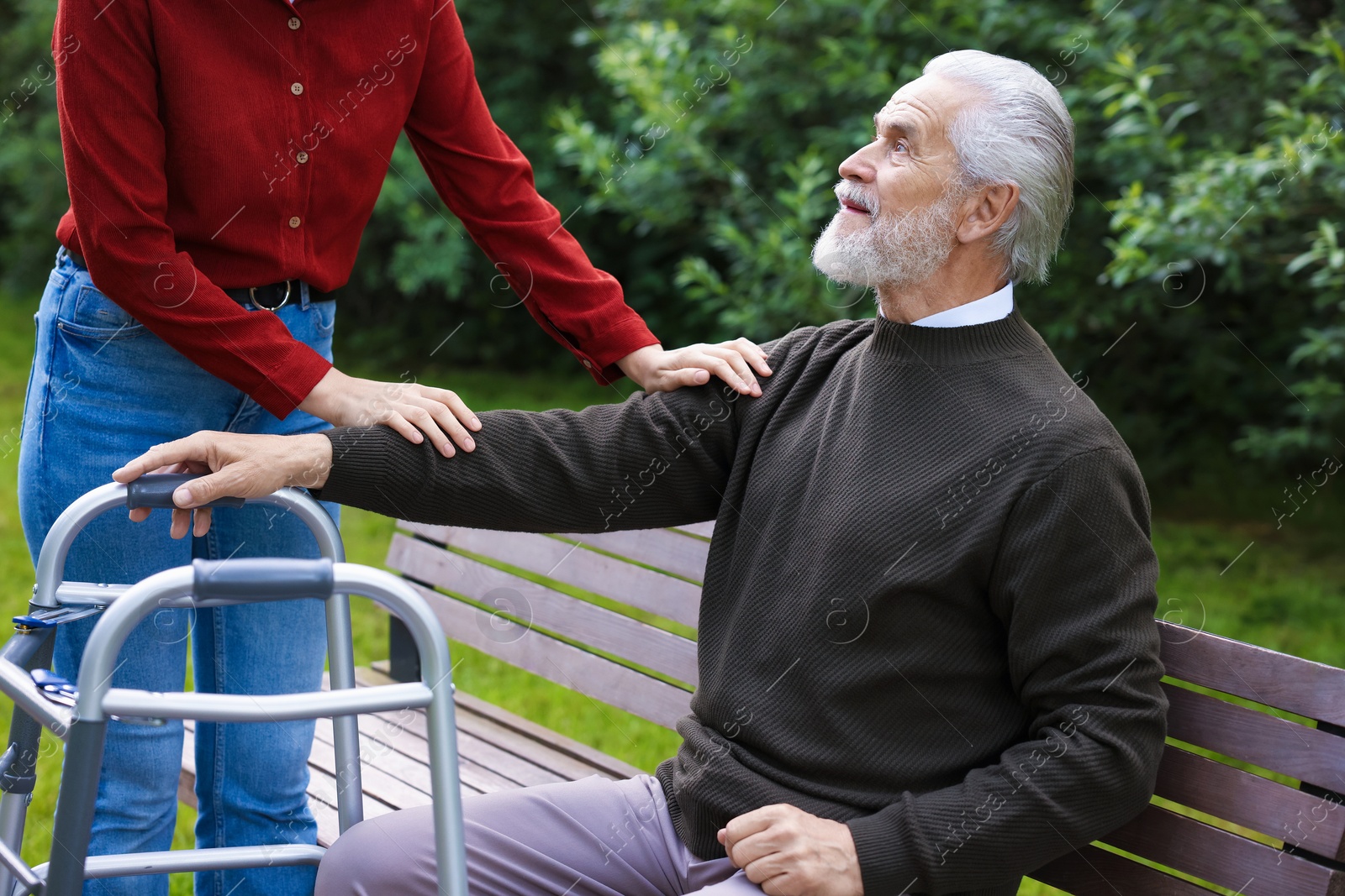 Caregiver supporting elderly man with walking frame outdoors, closeup Photo of Caregiver supporting elderly man with walking frame outdoors, closeup