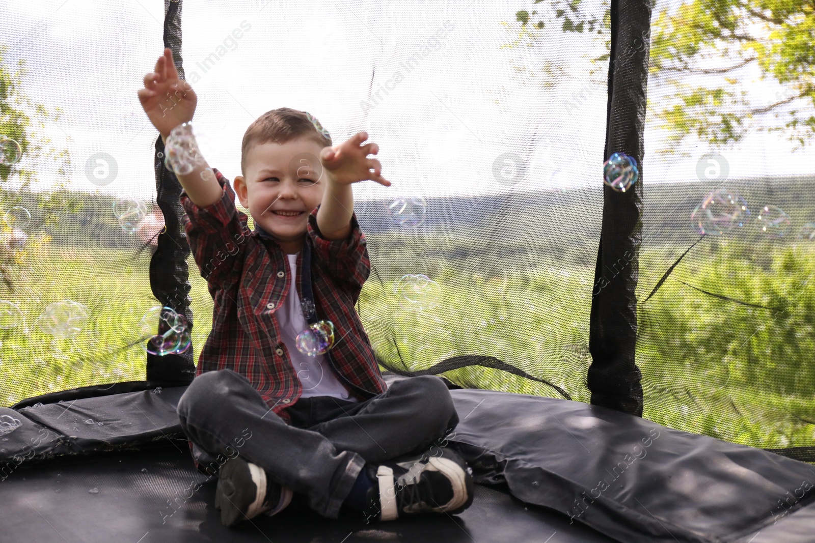Happy boy playing with soap bubbles on trampoline outdoors Photo of Happy boy playing with soap bubbles on trampoline outdoors