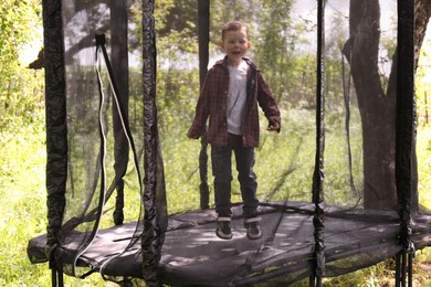 Photo of Little boy having fun on trampoline outdoors