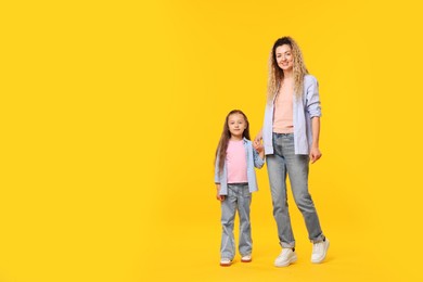 Photo of Family. Happy mother and her daughter on yellow background. Space for text