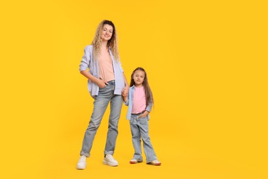 Photo of Family. Happy mother and her daughter on yellow background. Space for text
