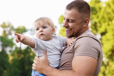Photo of Smiling dad and his newborn baby outdoors. Happy Father's Day