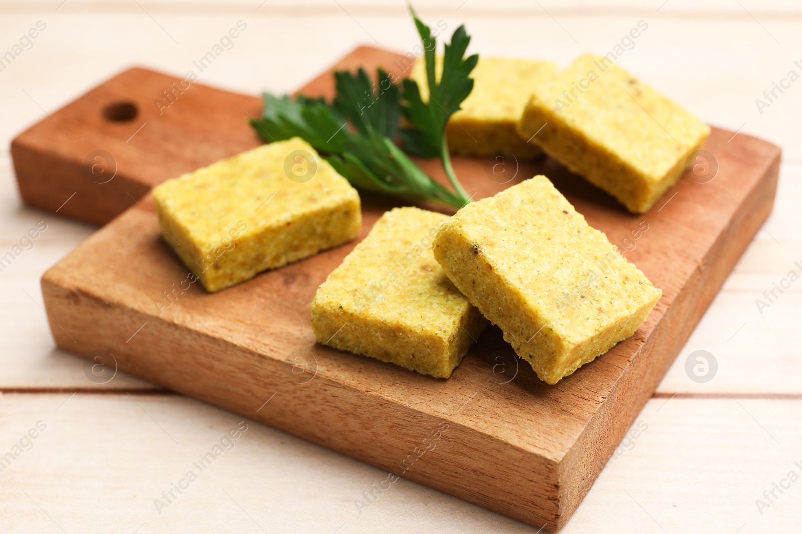 Aromatic bouillon cubes and parsley on wooden table, closeup Photo of Aromatic bouillon cubes and parsley on wooden table, closeup