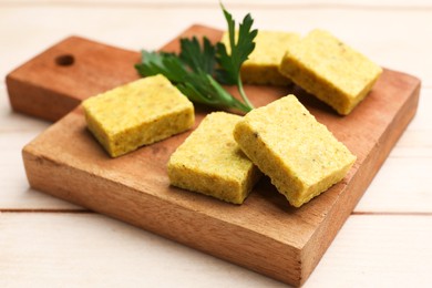 Photo of Aromatic bouillon cubes and parsley on wooden table, closeup
