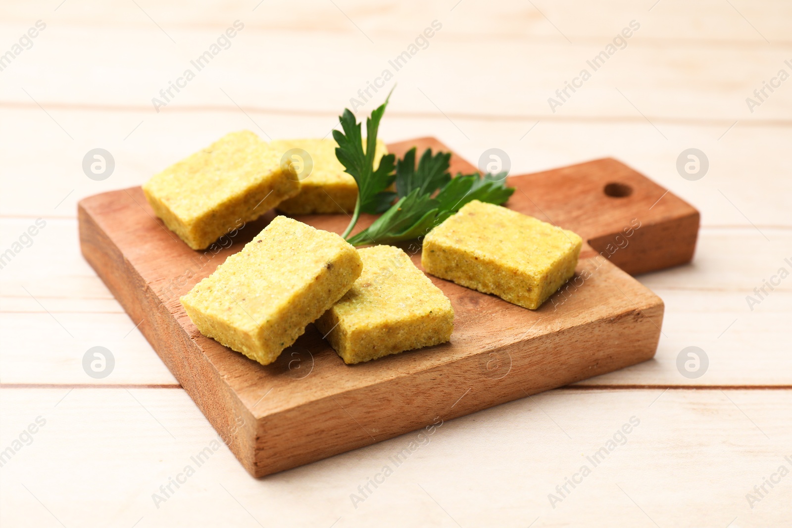 Photo of Aromatic bouillon cubes and parsley on wooden table, closeup