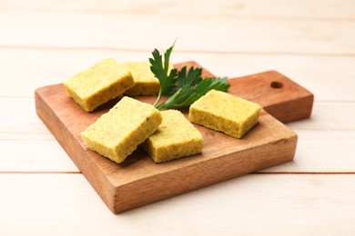 Photo of Aromatic bouillon cubes and parsley on wooden table, closeup