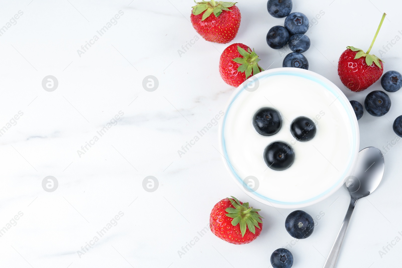 Tasty yoghurt with blueberries and strawberries in bowl on white marble table, flat lay. Space for text Photo of Tasty yoghurt with blueberries and strawberries in bowl on white marble table, flat lay. Space for text