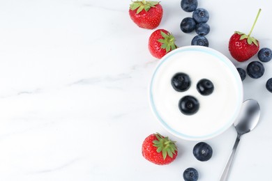 Photo of Tasty yoghurt with blueberries and strawberries in bowl on white marble table, flat lay. Space for text