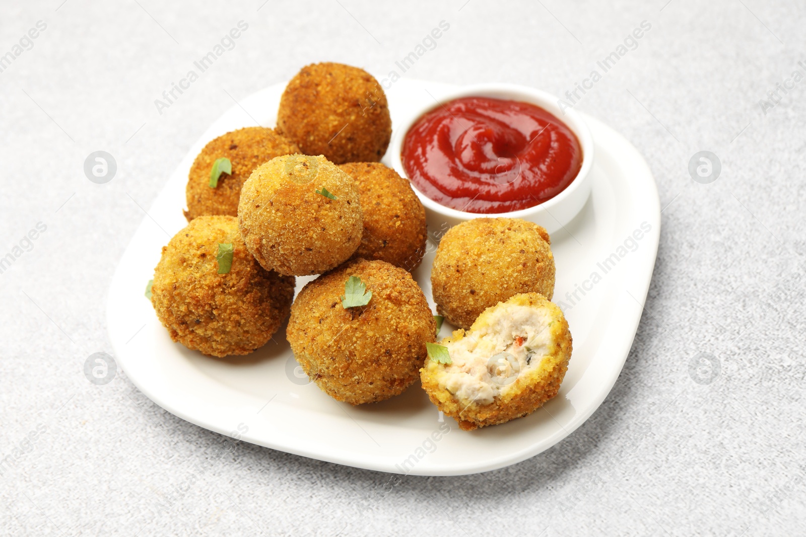 Delicious fried croquette balls with parsley and ketchup on grey textured table, closeup Photo of Delicious fried croquette balls with parsley and ketchup on grey textured table, closeup