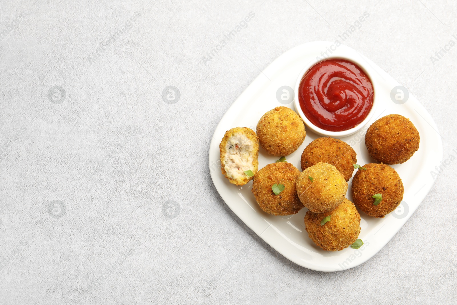 Delicious fried croquette balls with parsley and ketchup on grey textured table, top view. Space for text Photo of Delicious fried croquette balls with parsley and ketchup on grey textured table, top view. Space for text