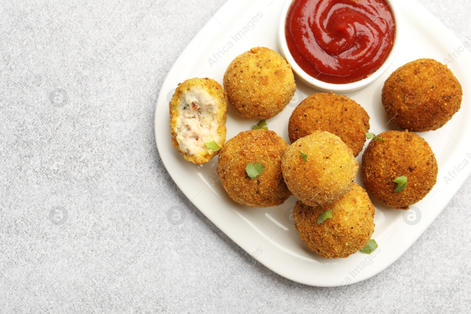 Delicious fried croquette balls with parsley and ketchup on grey textured table, top view. Space for text Photo of Delicious fried croquette balls with parsley and ketchup on grey textured table, top view. Space for text