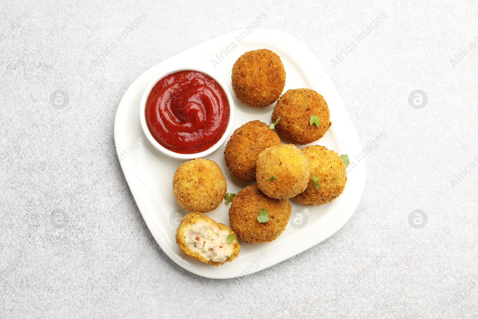 Delicious fried croquette balls with parsley and ketchup on grey textured table, top view Photo of Delicious fried croquette balls with parsley and ketchup on grey textured table, top view