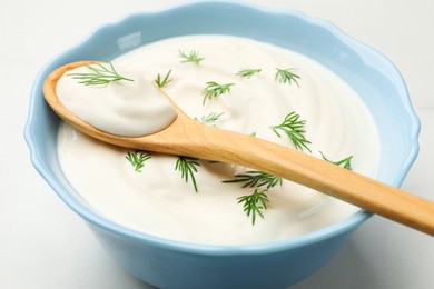 Photo of Tasty sour cream with dill on white table, closeup