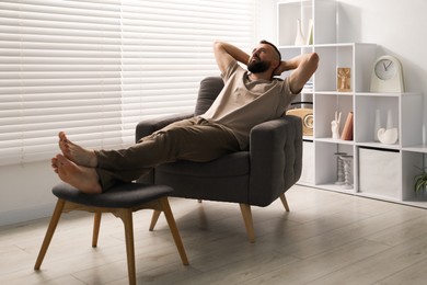 Photo of Harmony. Man relaxing in comfortable armchair at home