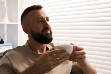 Photo of Harmony. Man with cup of drink at home