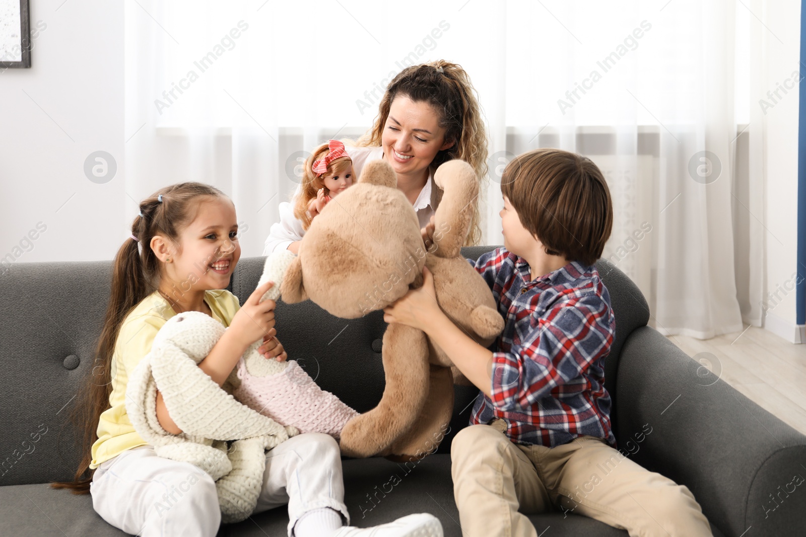 Children and their mother playing with different toys on sofa at home Photo of Children and their mother playing with different toys on sofa at home